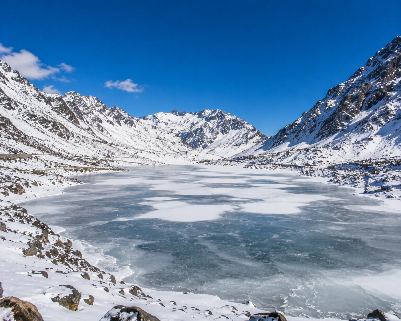 Sweeping winter landscape of frozen Sela Lake in Arunachal Pradesh surrounded by snow-covered mountain walls.