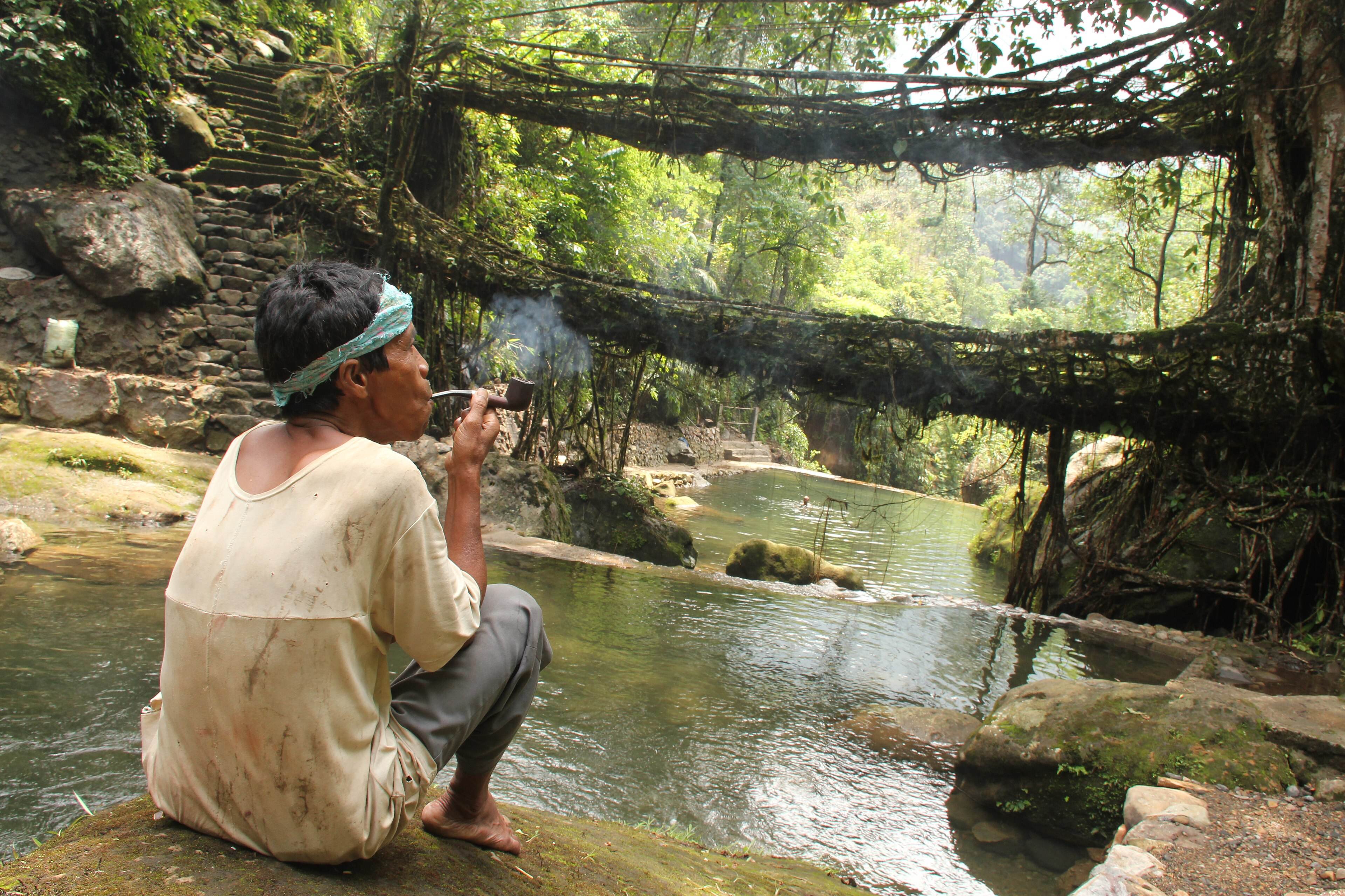 A trekker resting by the root bridges and stream at Nongriat