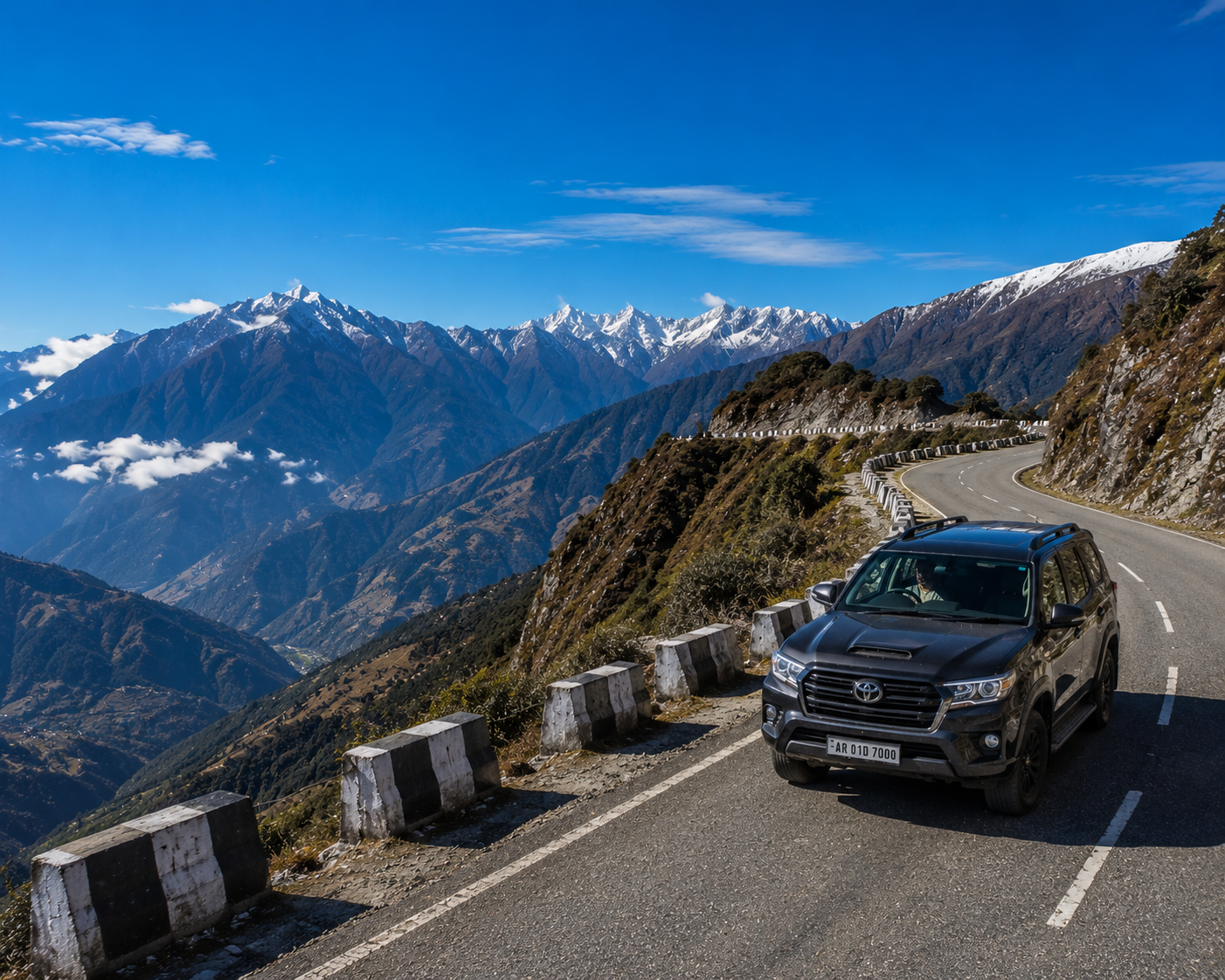 A premium 4x4 travel vehicle driving along a scenic, winding mountain highway ridge in Arunachal Pradesh under a clear blue alpine sky."