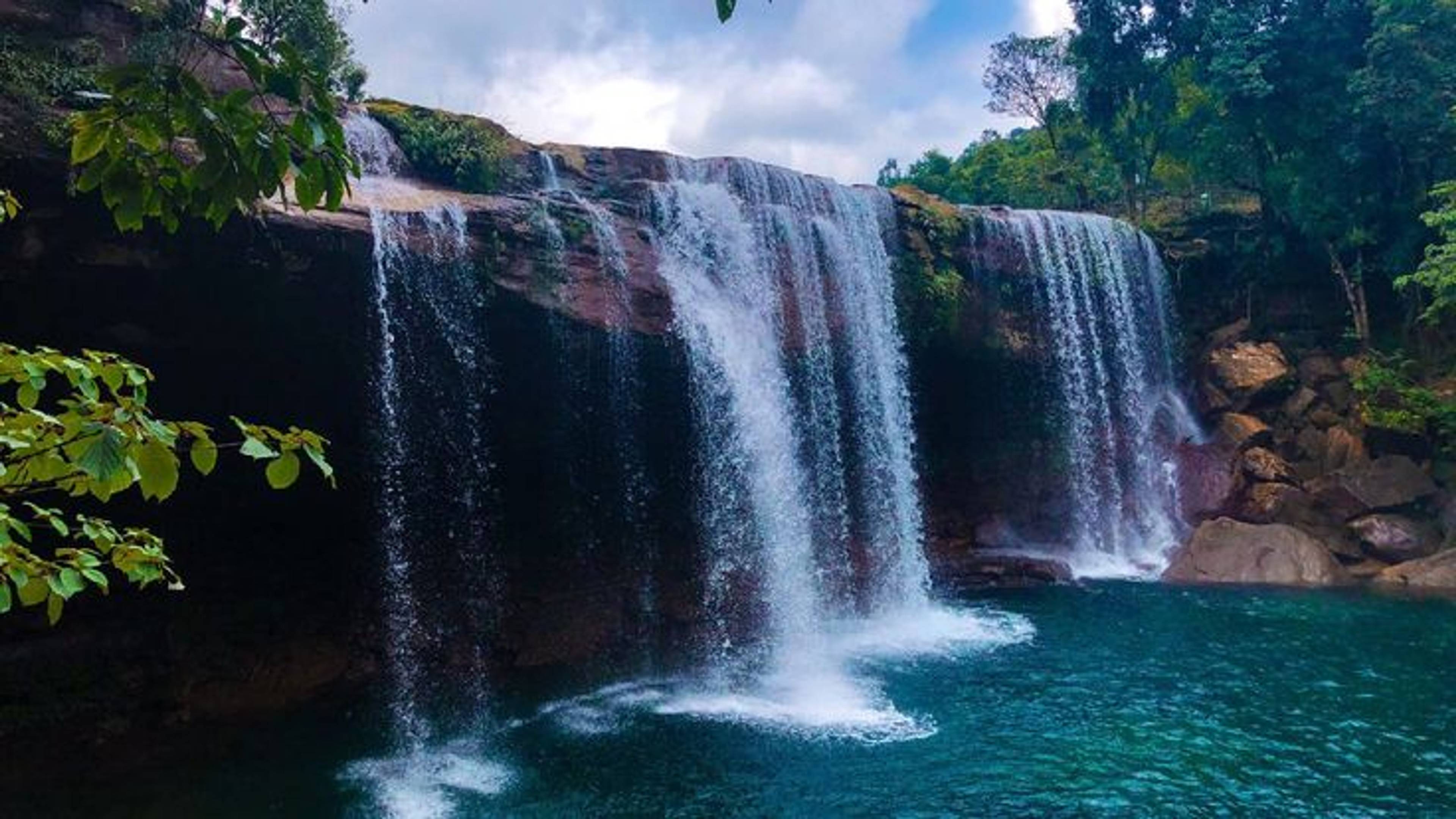 A stunning view of Krang Suri Falls in Meghalaya featuring its deep turquoise-blue natural pool and stone-paved walkway