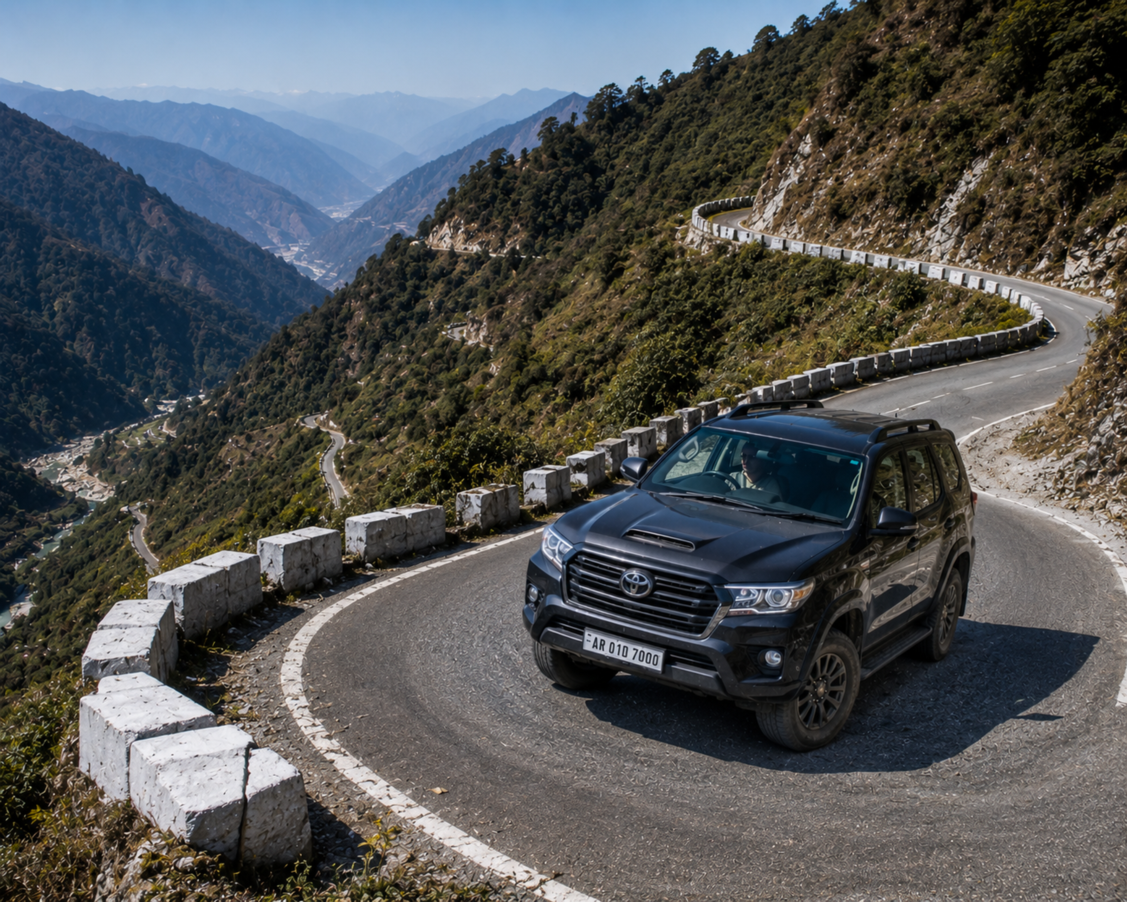 A premium 4x4 travel vehicle driving carefully up a sharp, paved mountain switchback bend in the outer Himalayan foothills."