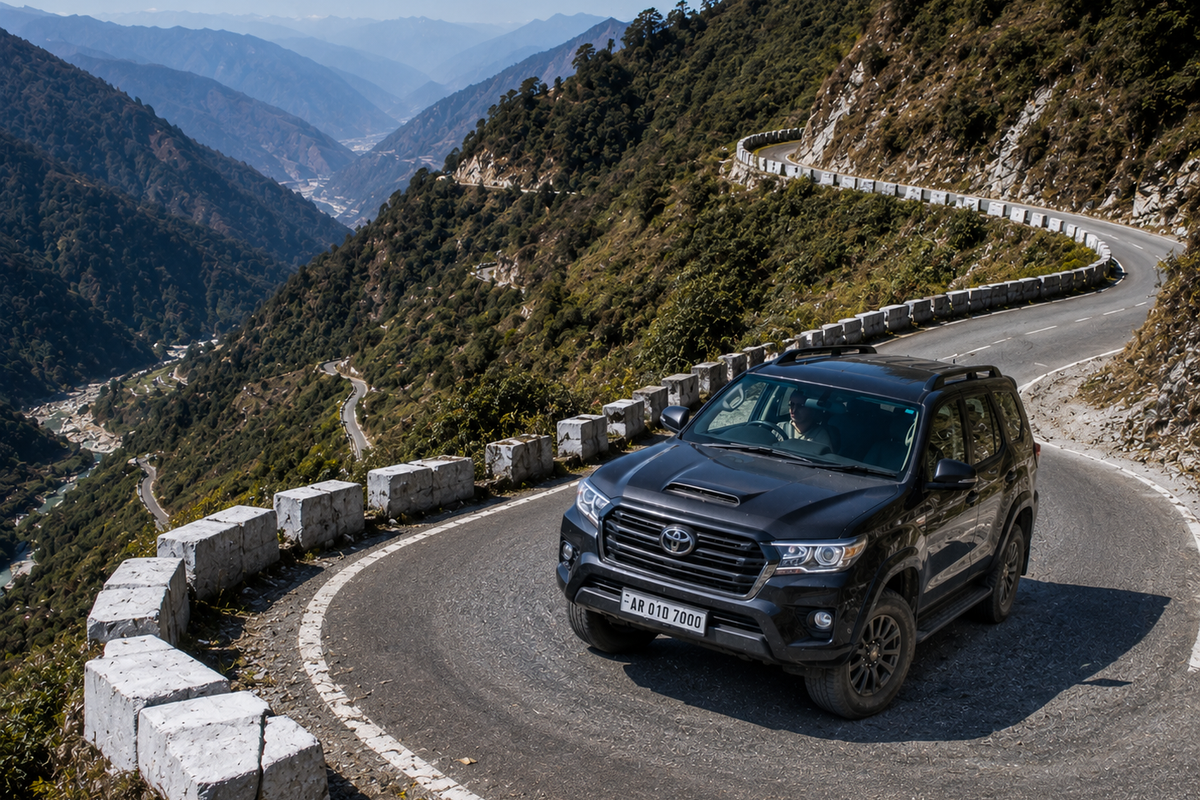 A premium 4x4 travel vehicle driving carefully up a sharp, paved mountain switchback bend in the outer Himalayan foothills."