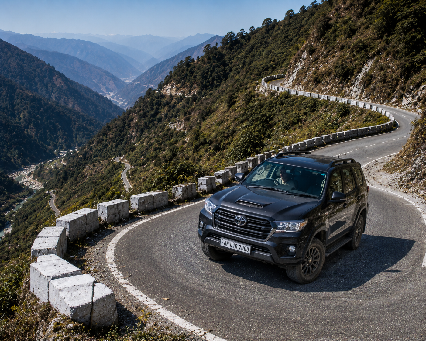 A premium 4x4 travel vehicle driving carefully up a sharp, paved mountain switchback bend in the outer Himalayan foothills."