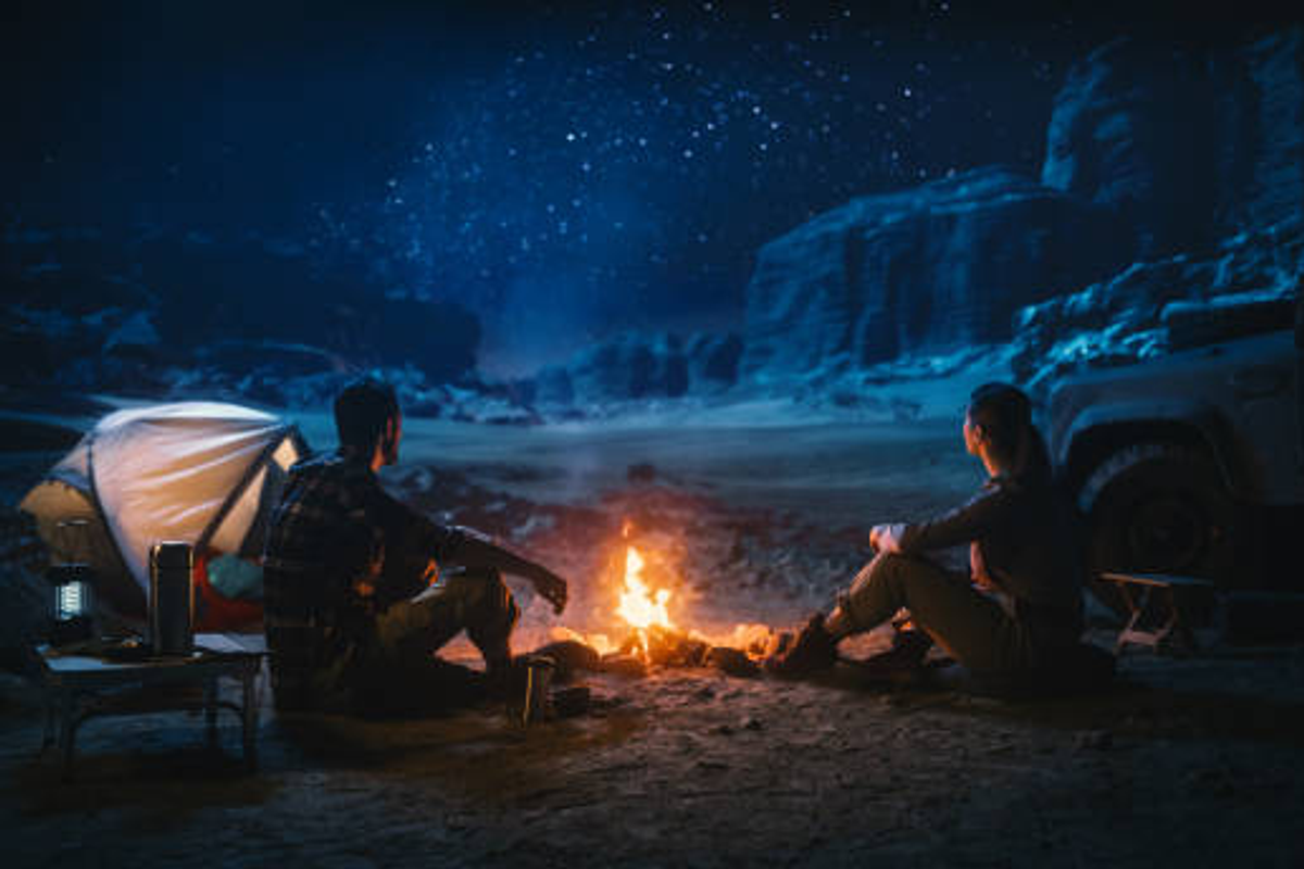 A traveler enjoying a campfire under a clear starry night sky in a remote village of Arunachal Pradesh.