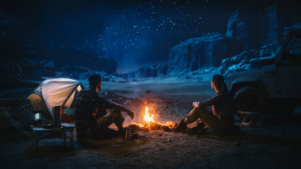 A traveler enjoying a campfire under a clear starry night sky in a remote village of Arunachal Pradesh.