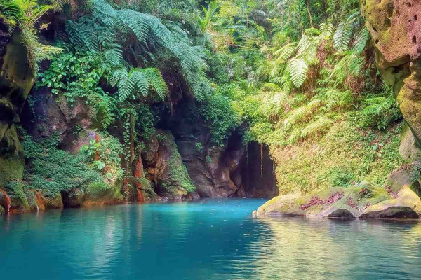 Wari Chora canyon in Meghalaya, hidden gem of Garo Hills with turquoise natural pool, moss‑covered rocks, tropical greenery, and cave formations.