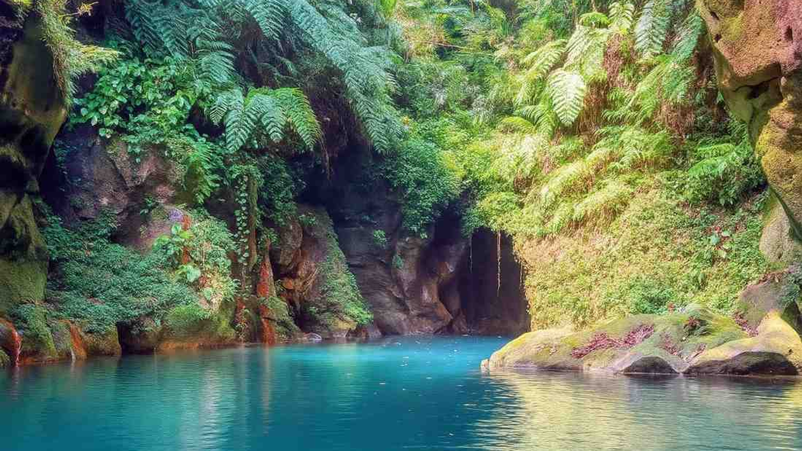 Wari Chora canyon in Meghalaya, hidden gem of Garo Hills with turquoise natural pool, moss‑covered rocks, tropical greenery, and cave formations.