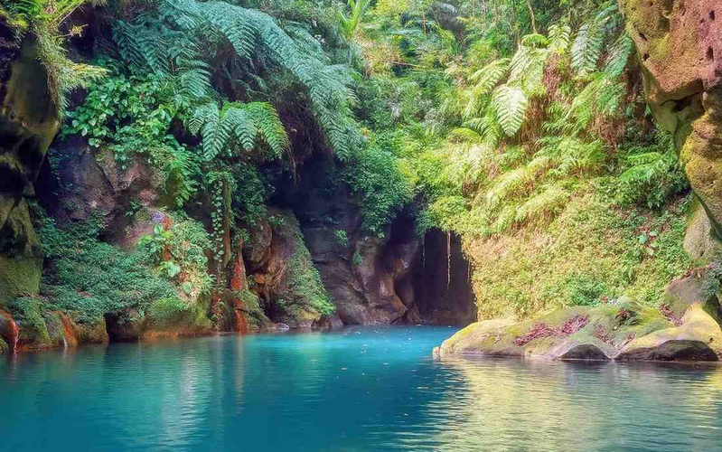 Wari Chora canyon in Meghalaya, hidden gem of Garo Hills with turquoise natural pool, moss‑covered rocks, tropical greenery, and cave formations.