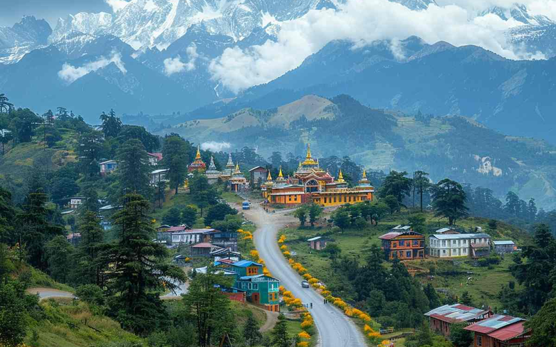 cenic view of Tawang Monastery featuring golden spires, a flower-lined road, and the snowy Himalayas behind.