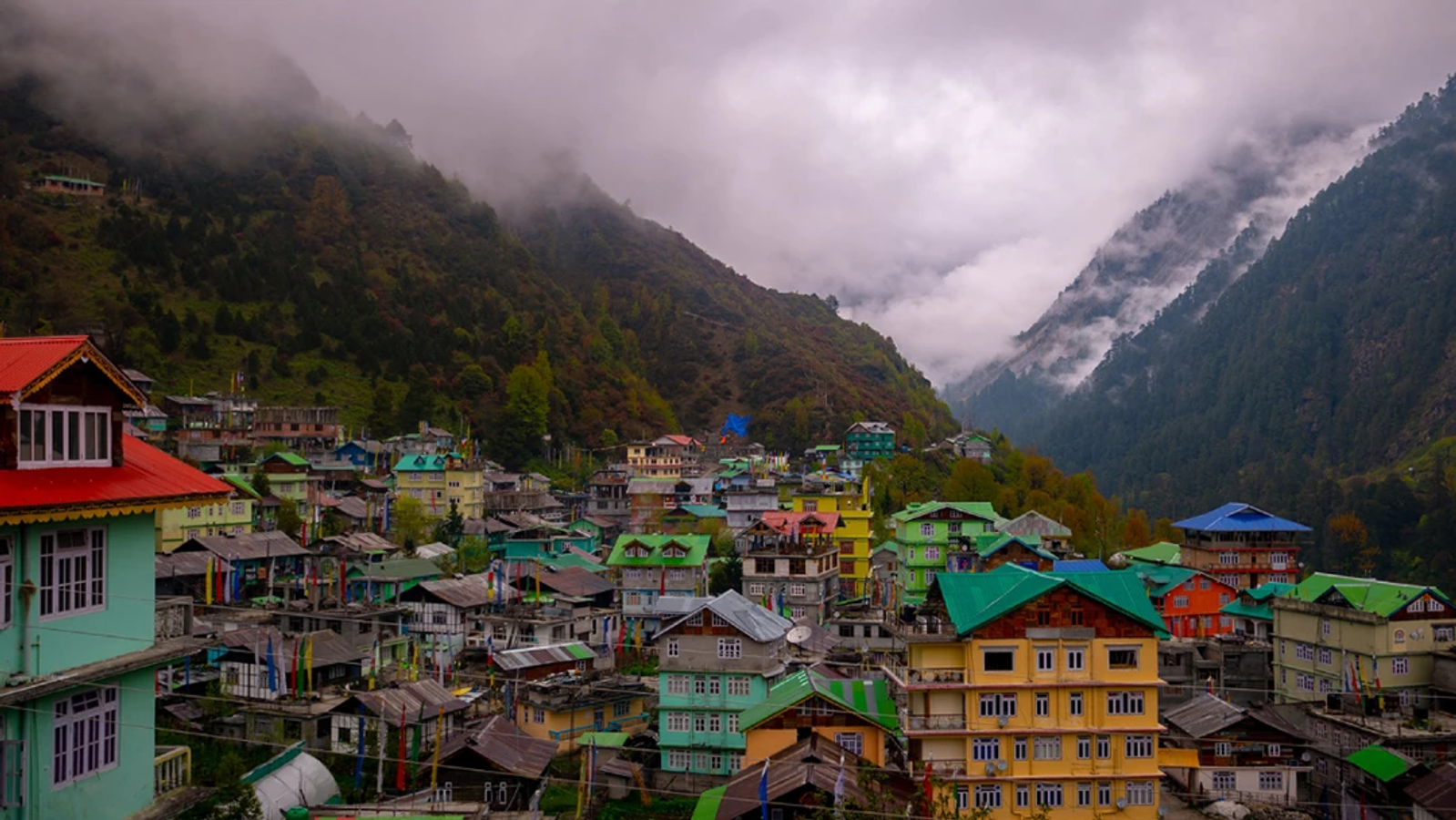 Wide landscape view of Lachen village in North Sikkim with traditional Himalayan architecture and a misty mountain backdrop.