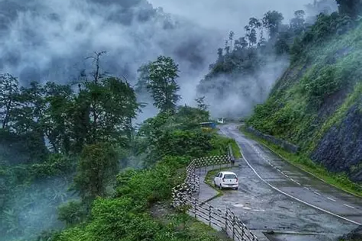  Misty mountain road with dense forest and parked car along winding curve in pasighat, Arunachal Pradesh