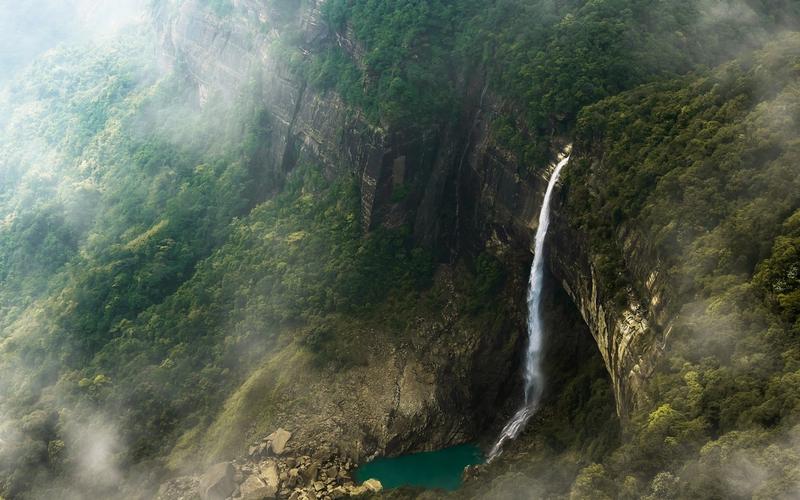 Traveler at Nohkalikai Falls Meghalaya monsoon season 2026 gear.]