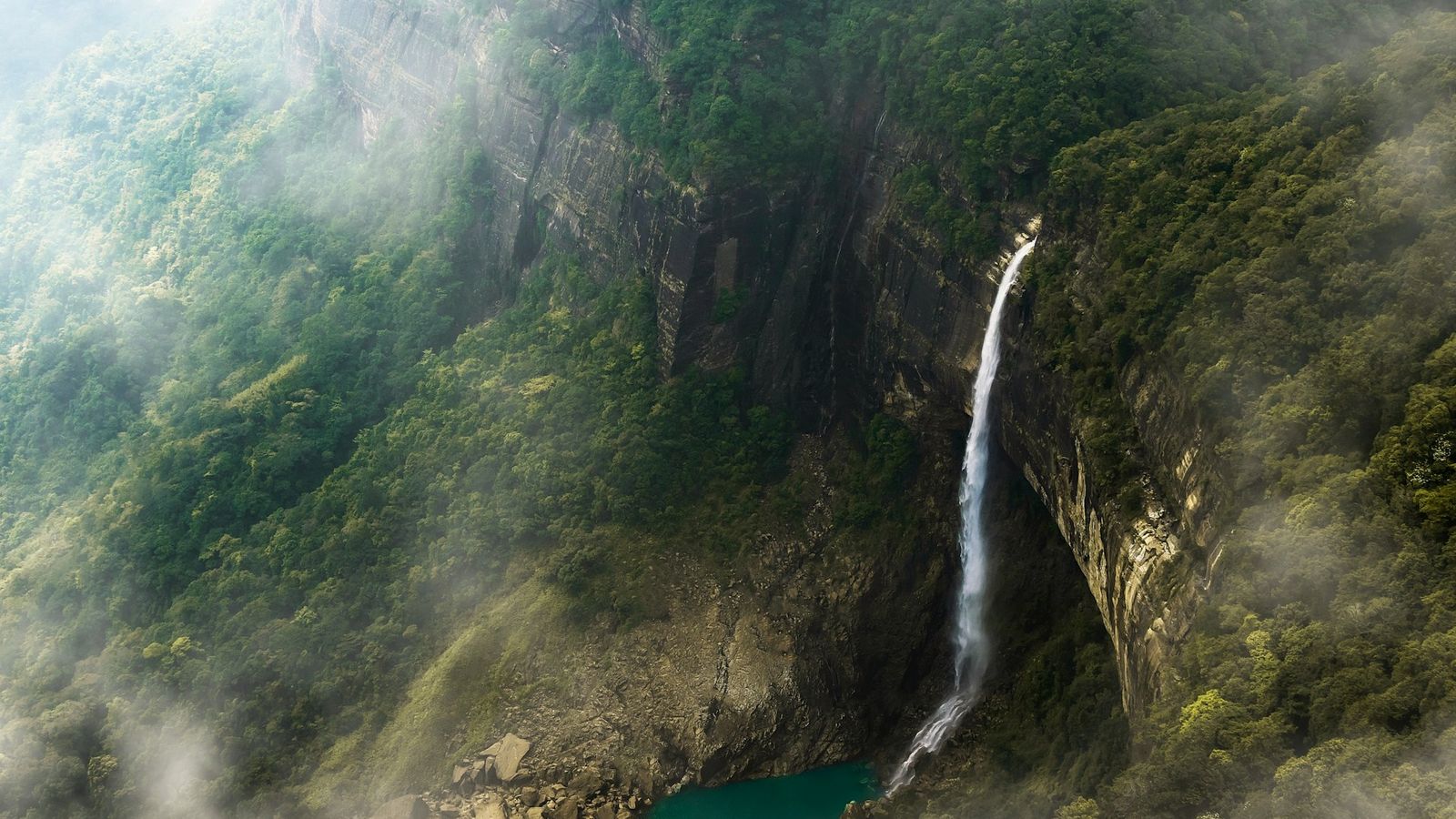 Traveler at Nohkalikai Falls Meghalaya monsoon season 2026 gear.]