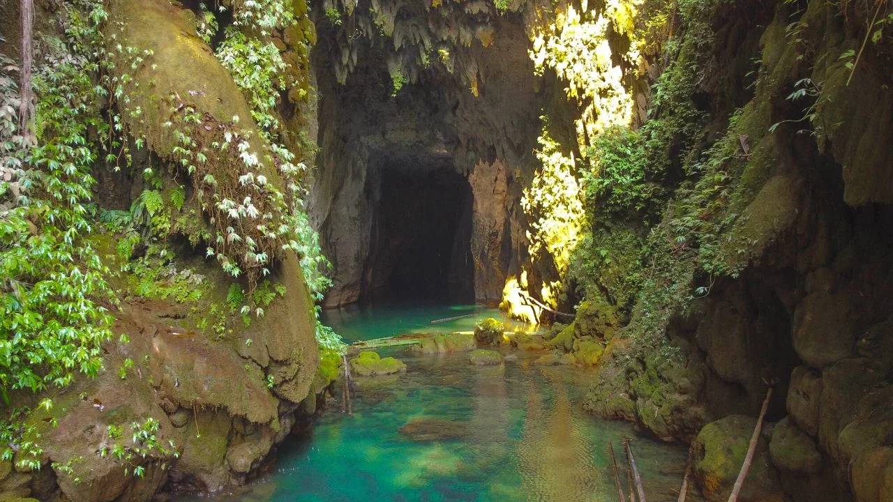 Waterfall pouring from the mouth of Krem Chympe cave into a blue pool