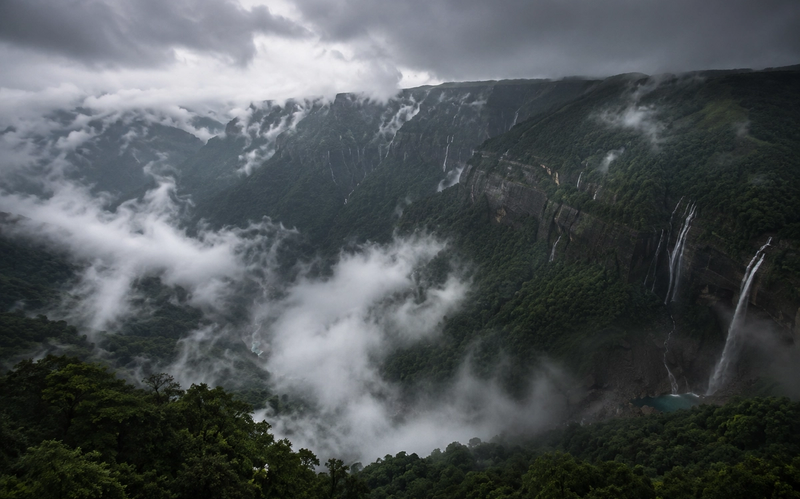 Cinematic aerial landscape of misty mountains and deep canyons in Cherrapunji Meghalaya during monsoon season.