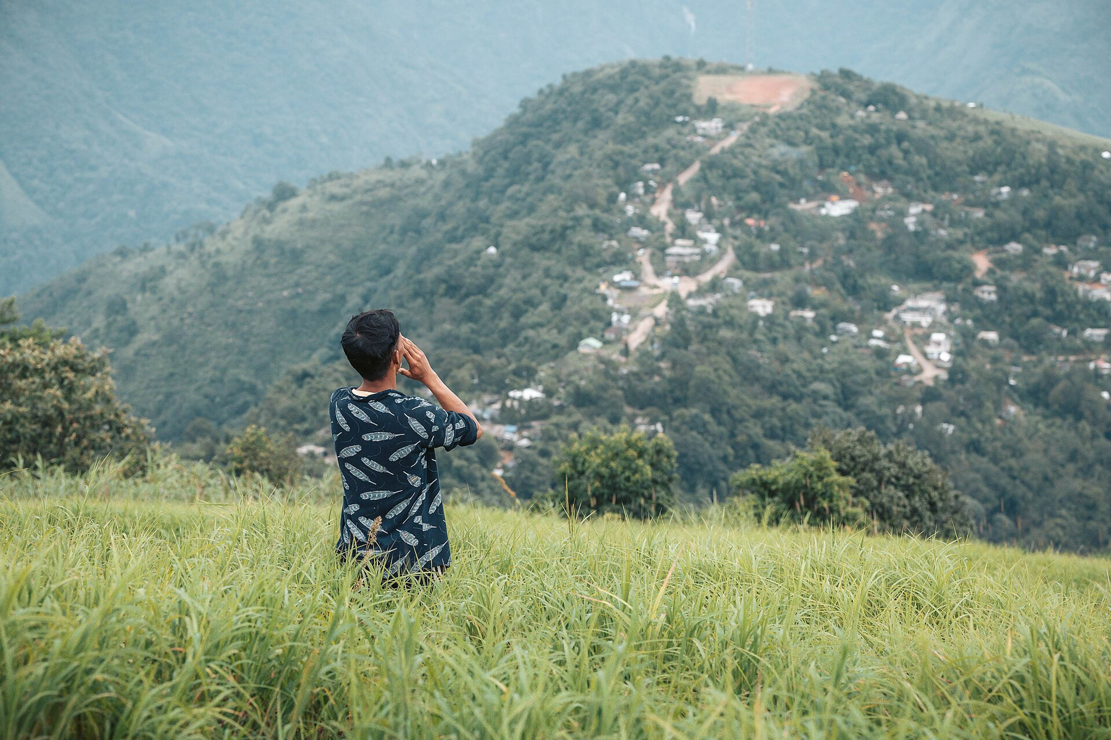 A visitor looking across the green valley towards Kongthong village on its ridge
