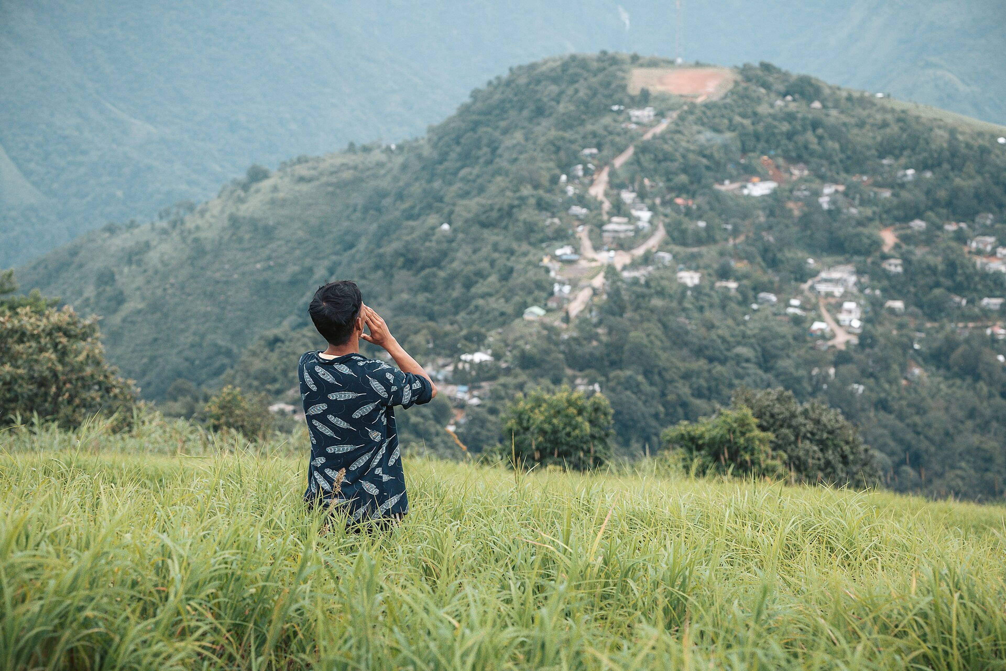 A visitor looking across the green valley towards Kongthong village on its ridge