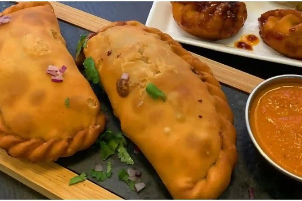 A plate of hot, deep-fried Sha Phaley bread served with spicy red Dalle Khursani chili chutney in a Namchi market.