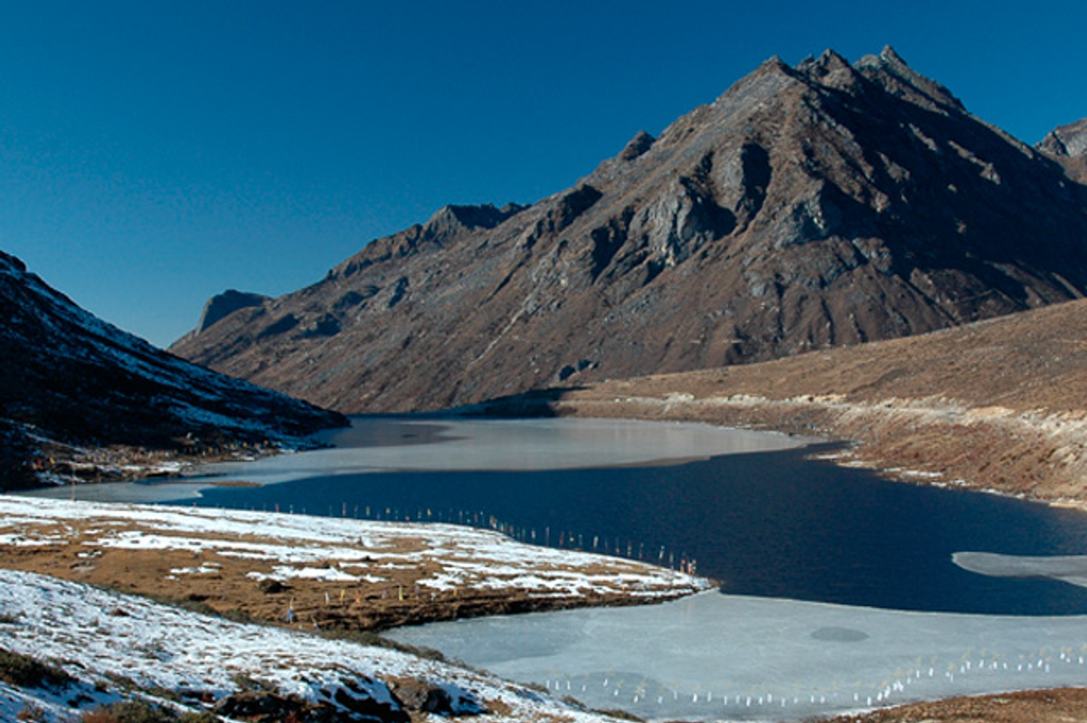 Serene landscape of P.T. Tso Lake in Tawang with snow-capped peaks reflecting in the still, high-altitude water.