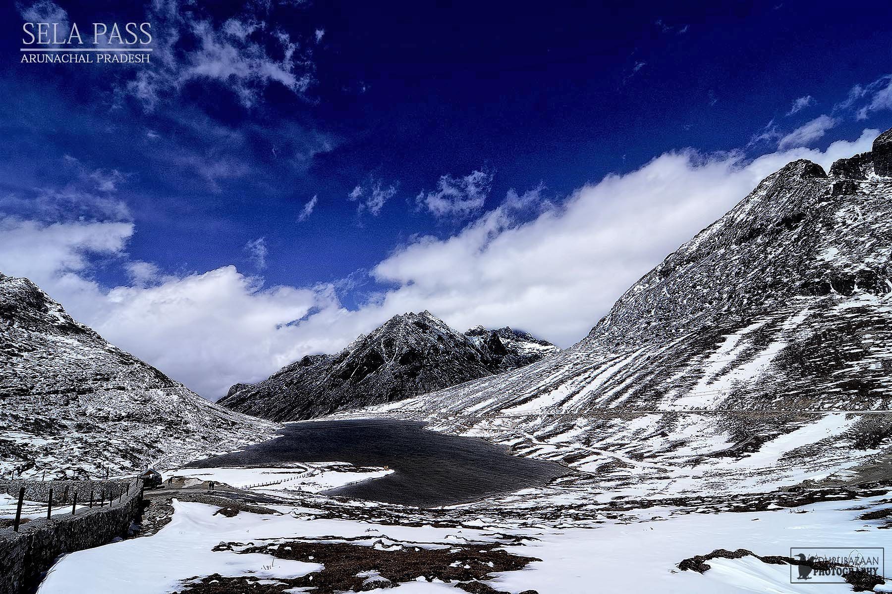 Sela Pass in Arunachal Pradesh with snow on the slopes and a frozen lake under a blue sky