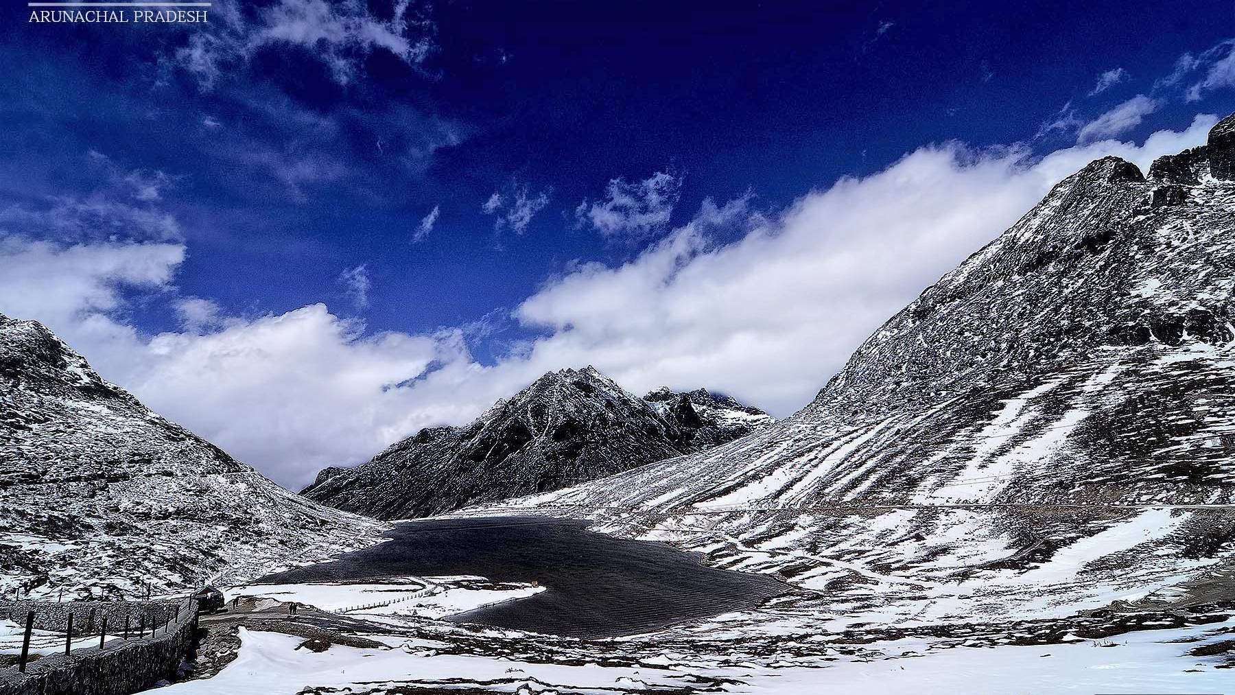 Sela Pass in Arunachal Pradesh with snow on the slopes and a frozen lake under a blue sky