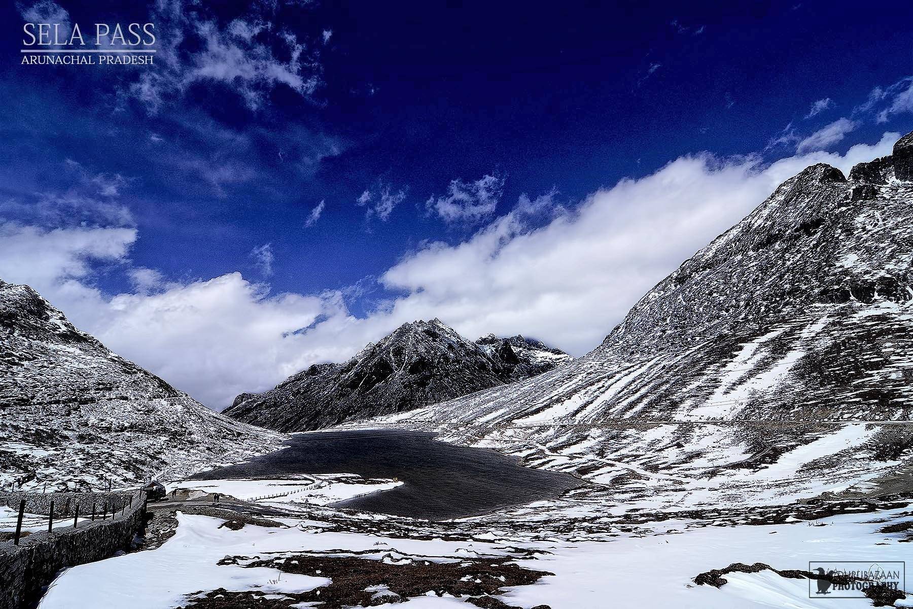 Sela Pass in Arunachal Pradesh with snow on the slopes and a frozen lake under a blue sky