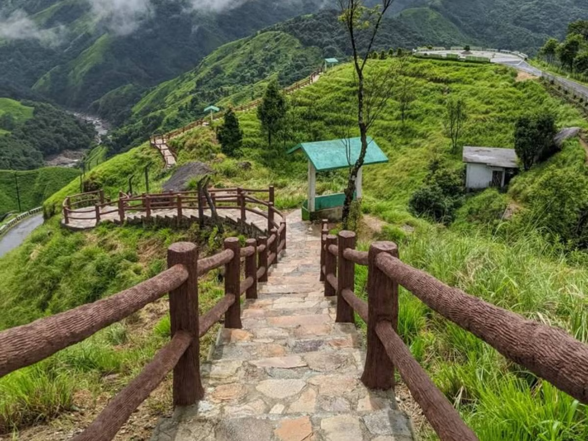 Stone path with wooden railings leading down a lush green hillside in meghalaya.