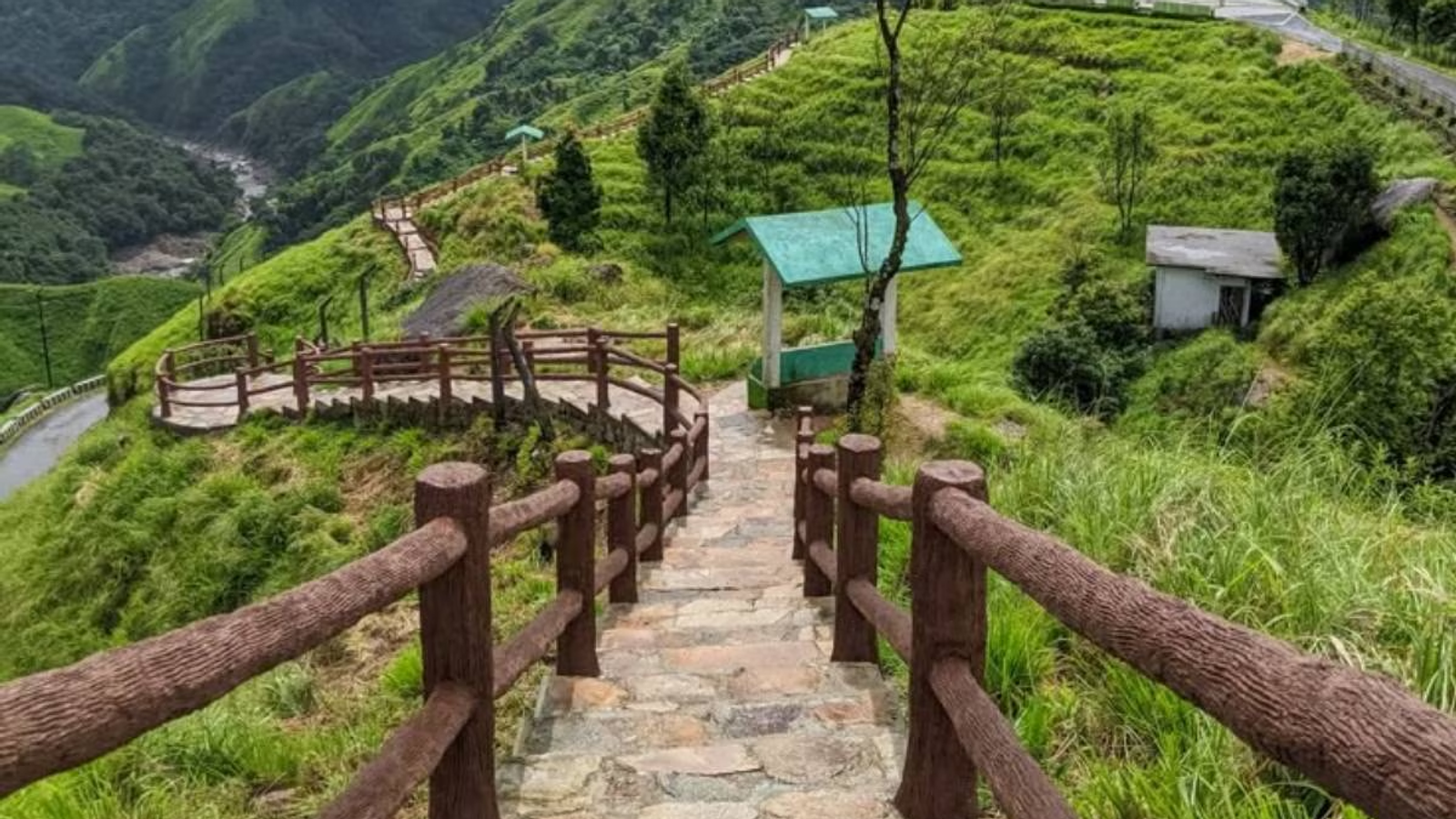 Stone path with wooden railings leading down a lush green hillside in meghalaya.
