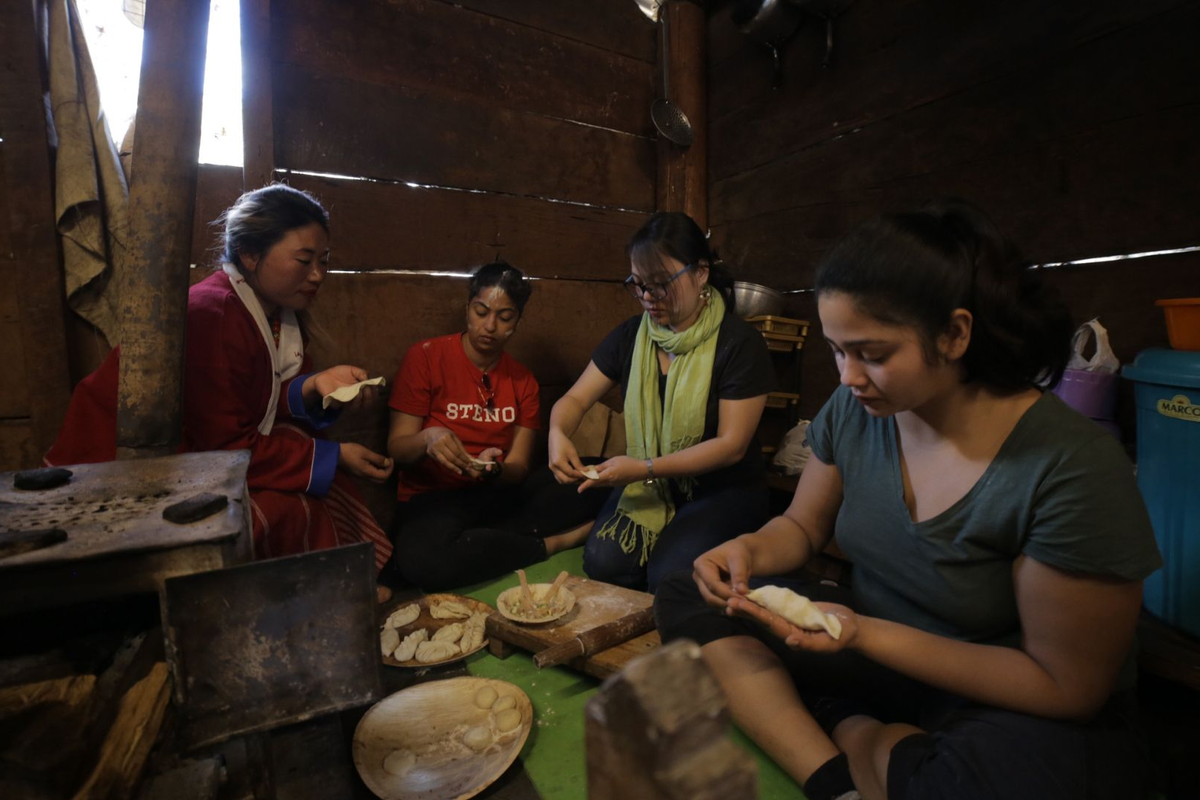 "A close-up lifestyle shot of a couple's hands folding traditional Sikkimese momos together during a private cooking class in a heritage homestay."
