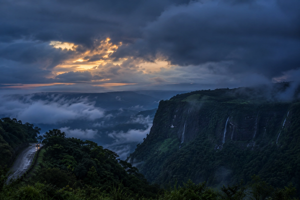 Cinematic twilight view of the Cherrapunji plateau under heavy monsoon clouds and thick mist, showcasing the atmospheric beauty of the region."
