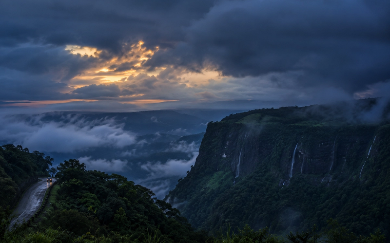 Cinematic twilight view of the Cherrapunji plateau under heavy monsoon clouds and thick mist, showcasing the atmospheric beauty of the region."