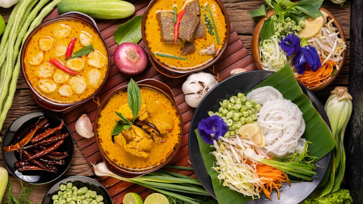 A colorful spread of traditional Meghalaya food including Jadoh, smoky Dohneiiong with black sesame, and Pukhlein rice cakes served with fresh local greens on a wooden table