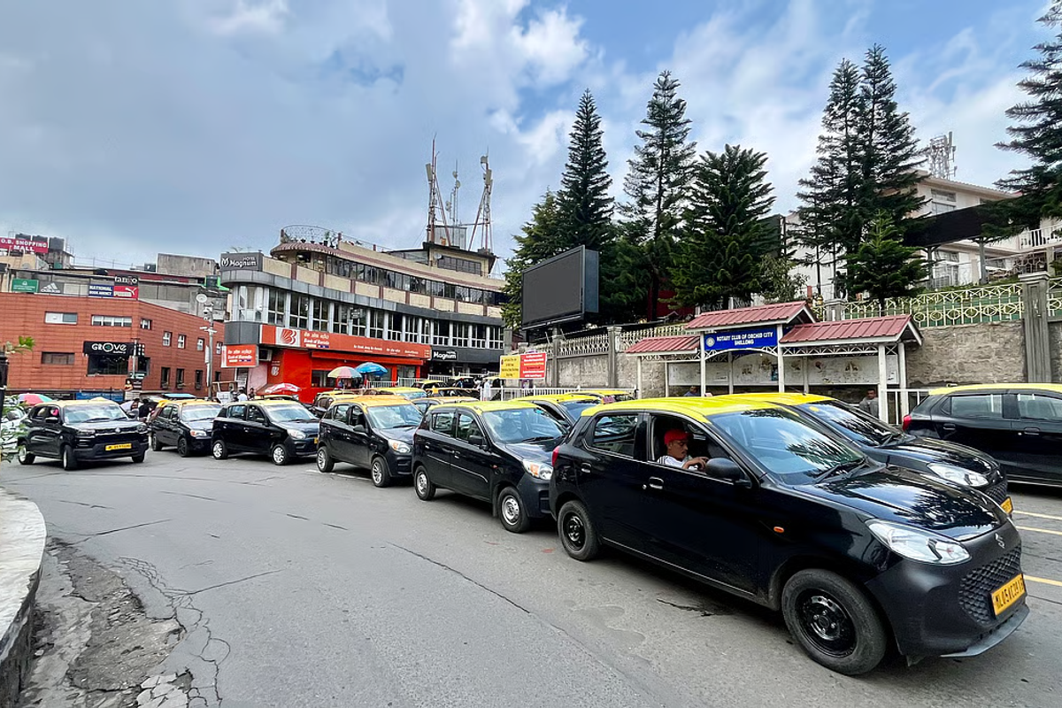 A yellow local taxi parked on a misty road in Shillong.
