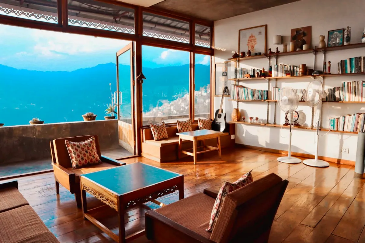A cozy traditional Sikkimese homestay room in Zuluk, featuring wooden interiors and a view of the misty mountains.