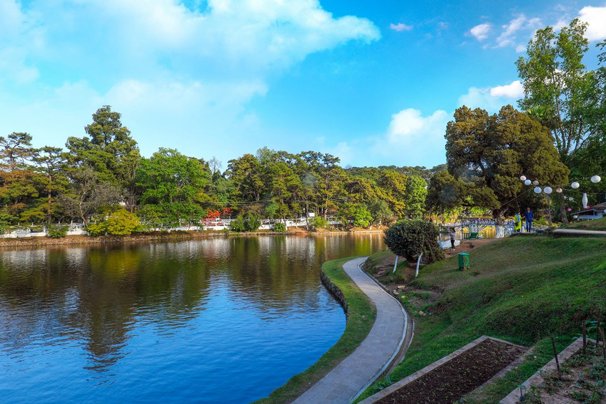 Ward's Lake Shillong with its iconic arched footbridge, calm blue waters, and lush manicured gardens on a clear morning in Meghalaya