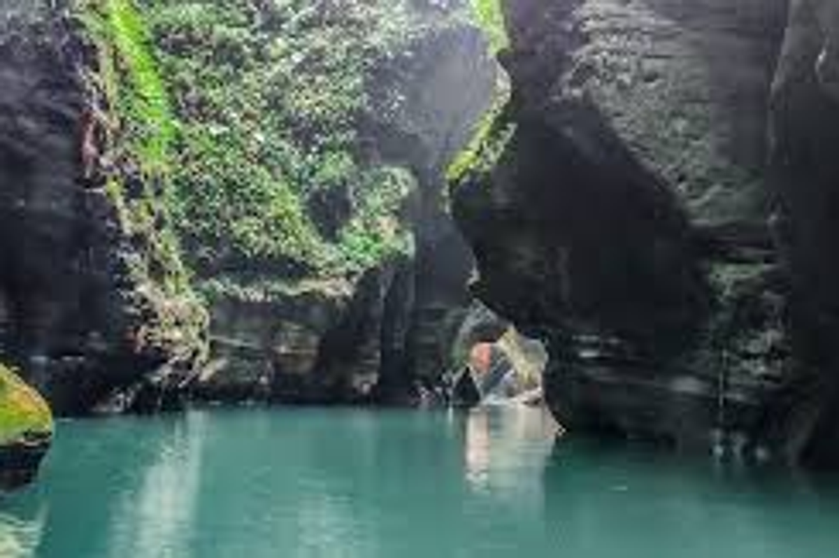 Clear turquoise blue water reflecting sunlight on the smooth rock walls of Wari Chora canyon.