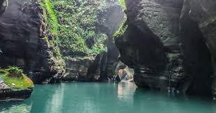 Clear turquoise blue water reflecting sunlight on the smooth rock walls of Wari Chora canyon.