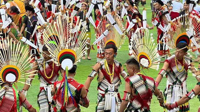 Naga dancers in traditional warrior dress performing in the arena at the Hornbill Festival in Kisama, Nagaland