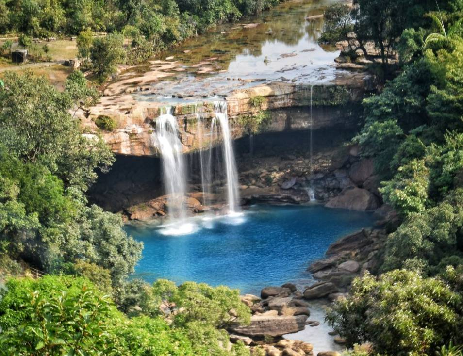 Krang Suri Falls Meghalaya blue water view with limestone rocks and lush greenery.