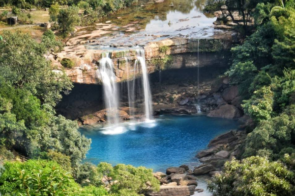 Krang Suri Falls Meghalaya blue water view with limestone rocks and lush greenery.