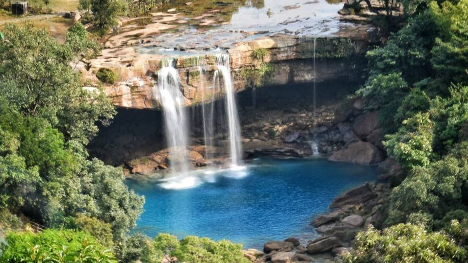 Krang Suri Falls Meghalaya blue water view with limestone rocks and lush greenery.
