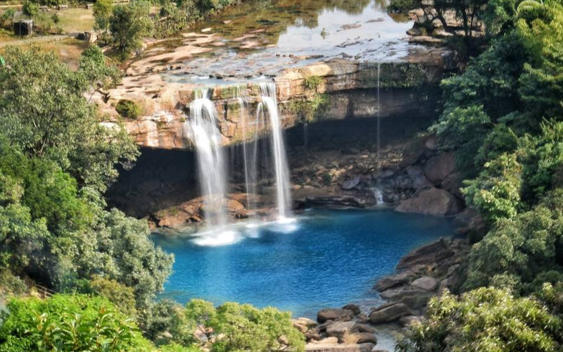 Krang Suri Falls Meghalaya blue water view with limestone rocks and lush greenery.