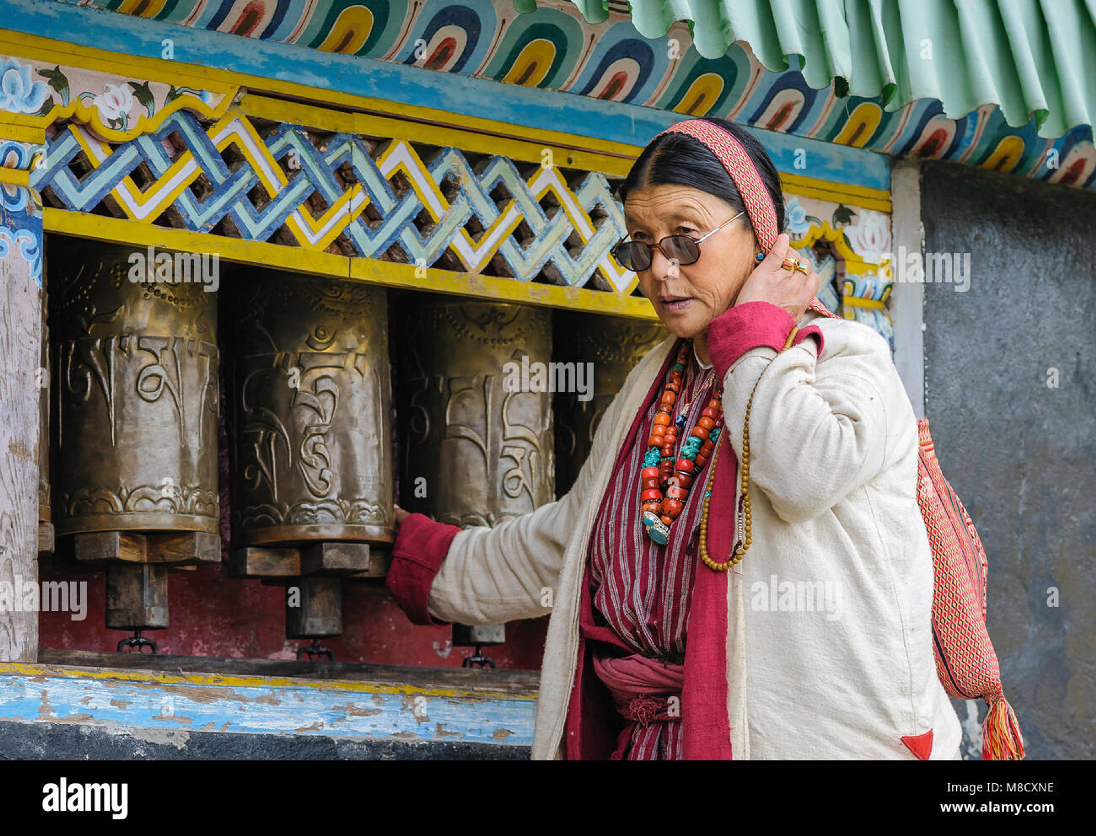 : A traditional Monpa man spinning a prayer wheel, representing the spiritual culture of Tawang, Arunachal Pradesh.