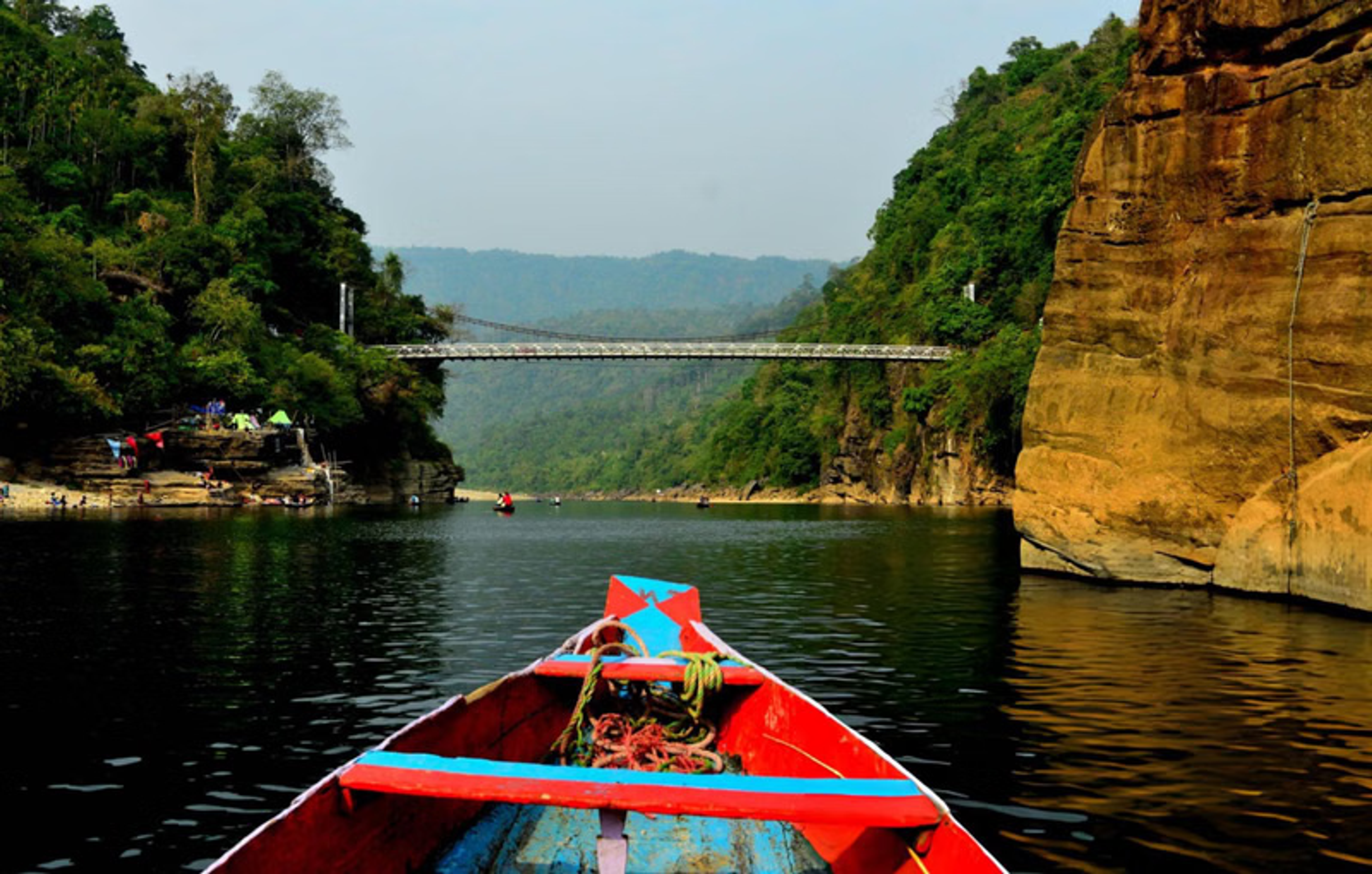A traditional wooden country boat floating on the crystal clear turquoise water of the Umngot River in Dawki Meghalaya under a clear sky