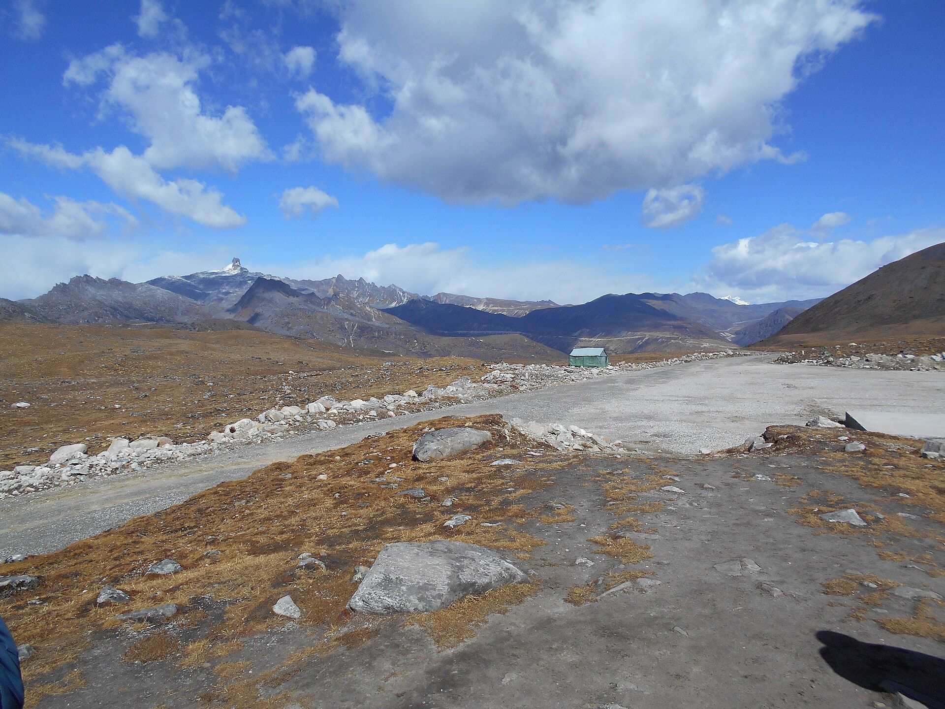 The wide, barren Bum La Pass at the India–China border with brown hills and snow peaks under a blue sky