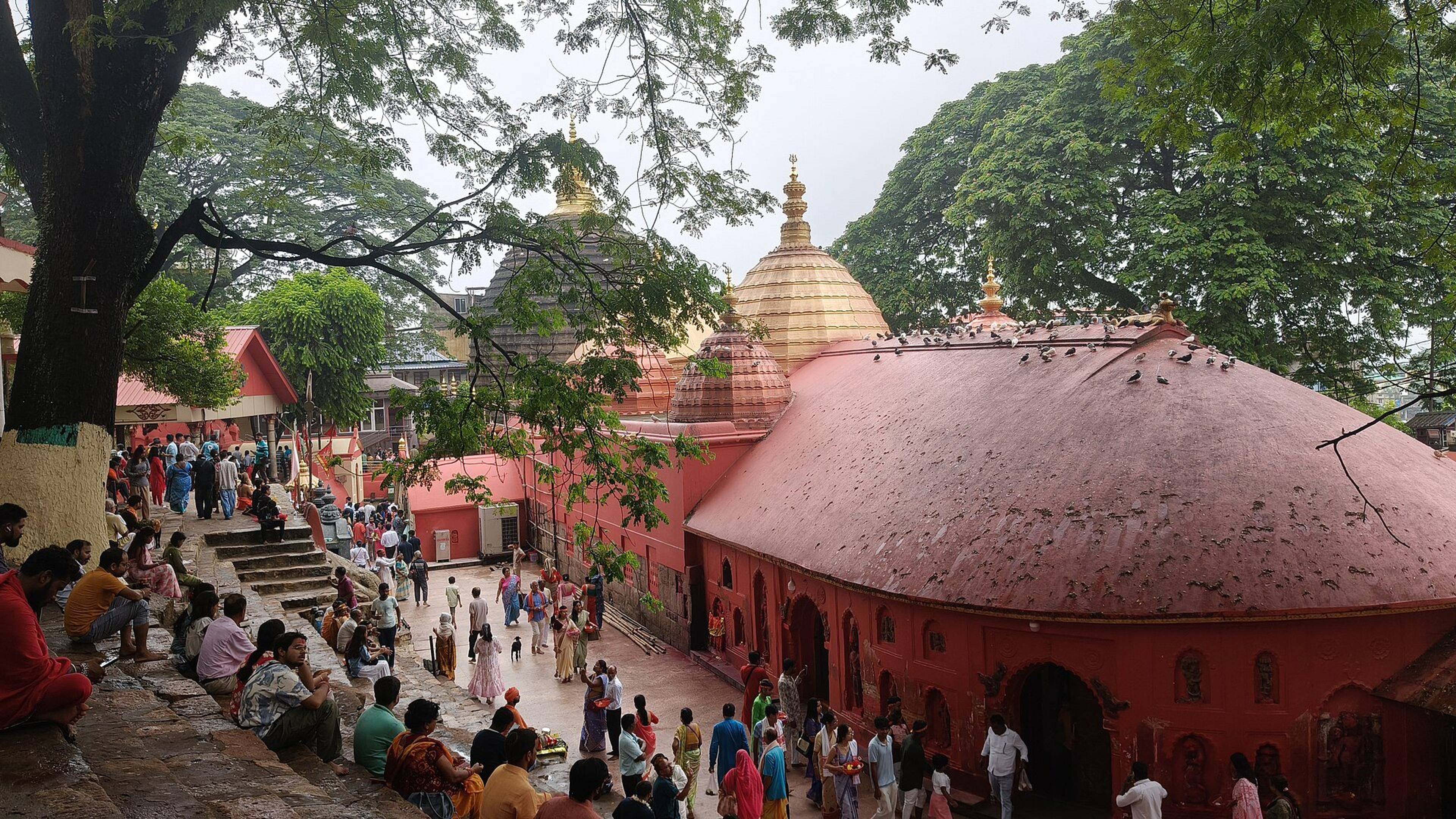 Devotees and visitors in the courtyard of Kamakhya Temple with its red and white domes