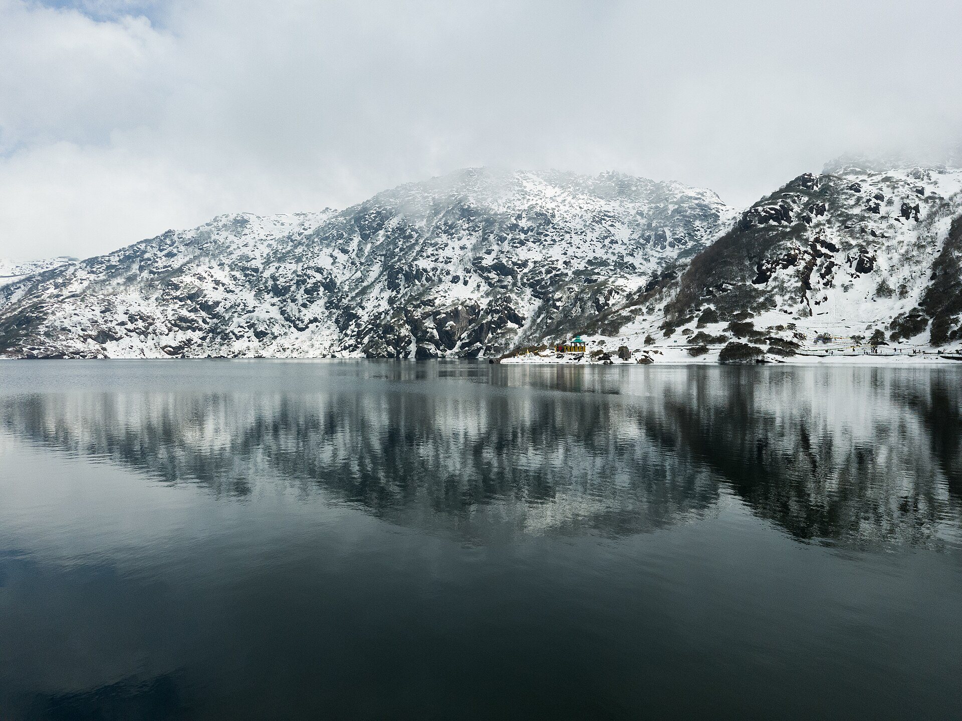Tsomgo Lake in East Sikkim with snow on the surrounding mountains and their reflection in the still water