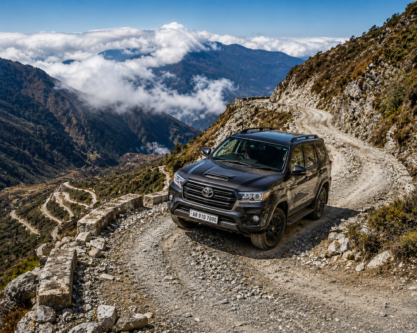 A premium 4x4 off-road SUV vehicle driving carefully up a sharp, gravel mountain switchback bend."