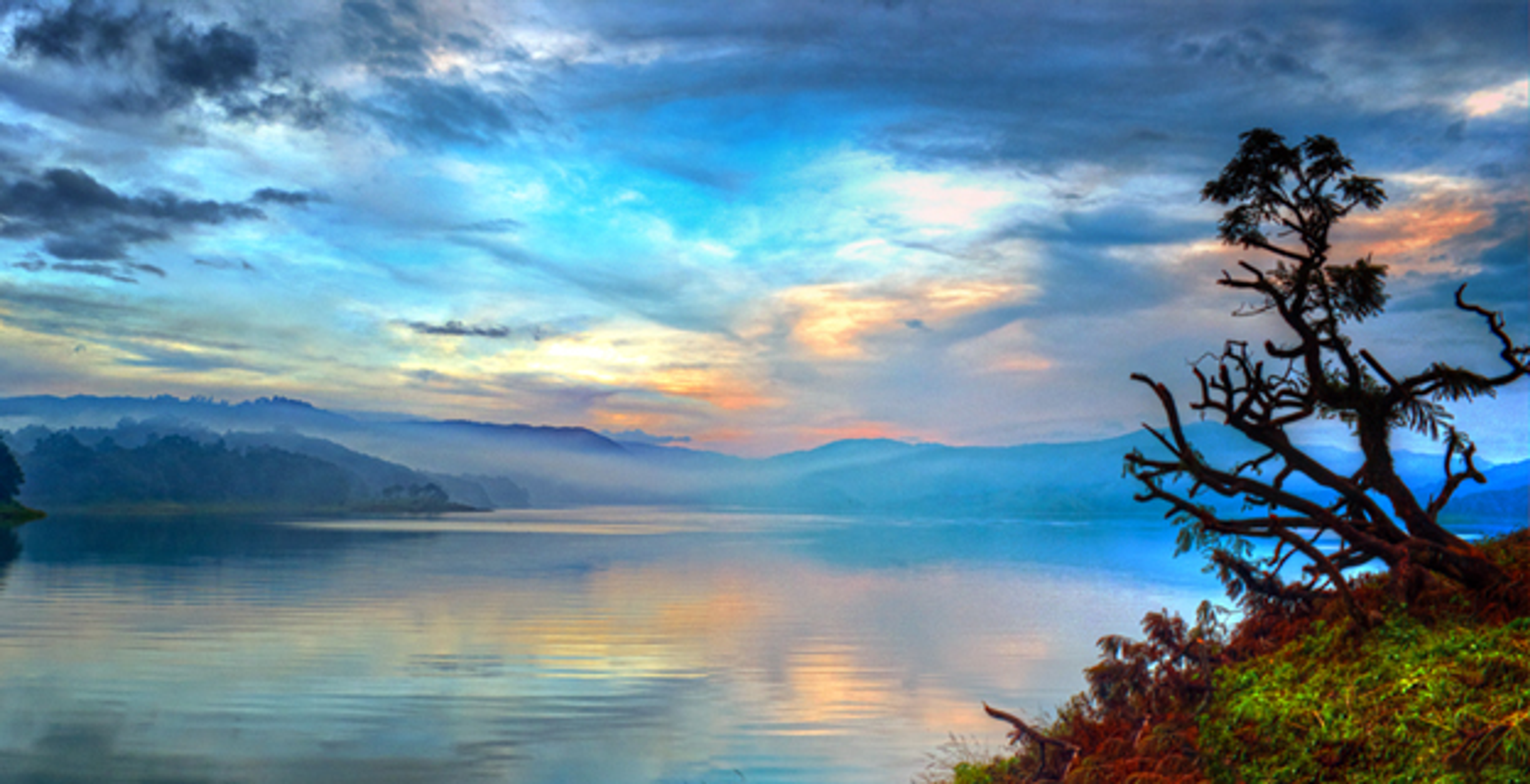 Panoramic view of Umiam Lake in Meghalaya surrounded by thick pine forests.