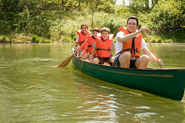Travelers wearing orange life jackets sitting inside a long wooden canoe inside a narrow rock gorge.